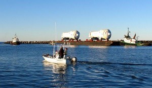 Fishermen in a small boat eye two ocean tugs as they push twin steam generators on a barge toward the Del Mar Boat Basin at Camp Pendleton early Saturday morning. The 65-foot-long components will be i