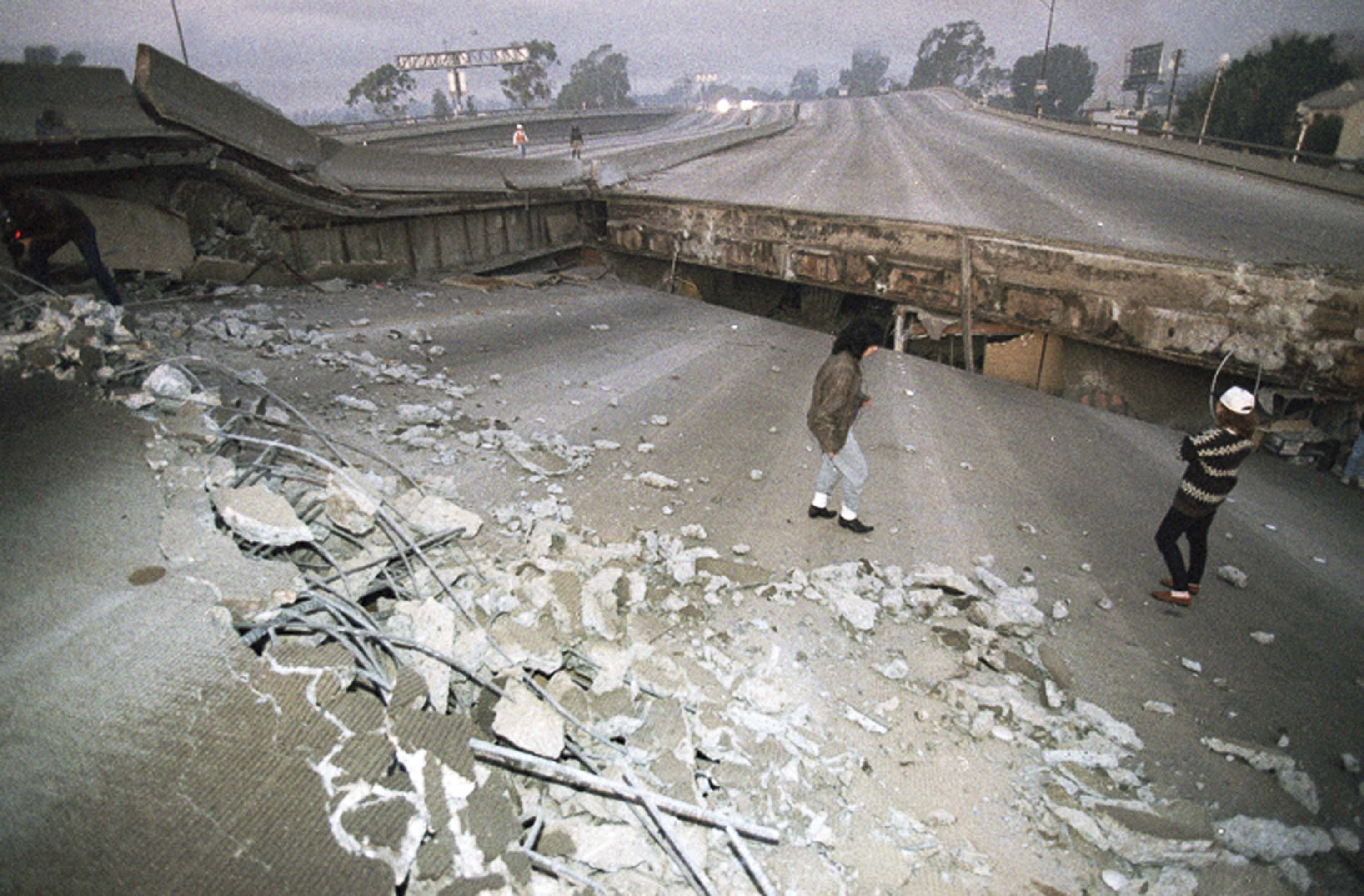 FILE - In this Jan. 17, 1994 file photo, Interstate 10, the Santa Monica Freeway, split and collapsed over La Cienega Boulevard following the Northridge quake in the predawn hours in Los Angeles. Twenty-five years ago this week, a violent, pre-dawn earthquake shook Los Angeles from its sleep, and sunrise revealed widespread devastation, with dozens killed and $25 billion in damage. (AP Photo/Eric Draper, File)