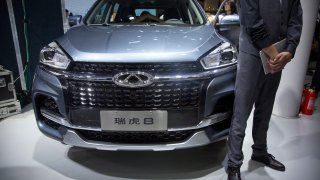 A staff member stands next to a Tiggo 8 SUV by Chinese automaker Chery after a press conference at the China Auto Show in Beijing. April 25, 2018. A California company says it will build and sell Chinese-designed automobiles in the U.S. at the end of next year or early in 2022.