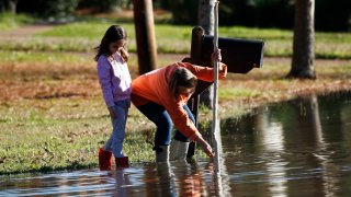 Barbara Beavers and her daughter measure rising floodwaters in Mississippi