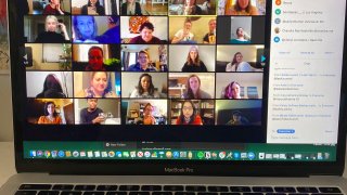A laptop shows people gathered together online for a virtual happy hour