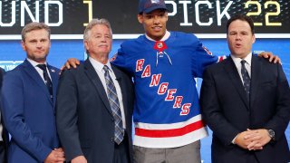 File photo of K'Andre Miller, second from right, wears a New York Rangers jersey and cap after being selected by the team during the NHL hockey draft in Dallas.
