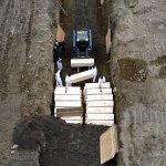 Workers wearing personal protective equipment bury bodies in a trench on Hart Island, Thursday, April 9, 2020, in the Bronx