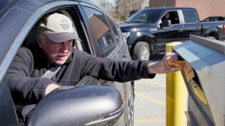 A voter drops his ballot into a collection box outside the Douglas County Election Commission office in Omaha, Neb., Friday, April 10, 2020. Officials in Nebraska are forging ahead with plans for the state's May 12 primary despite calls to delay the election or go to all vote by mail.