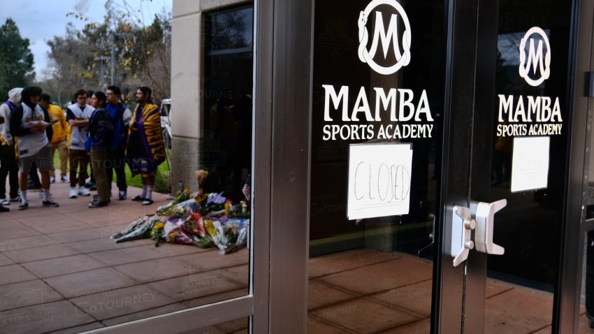 FILE – In this Jan. 26, 2020, file photo, Los Angeles Lakers fans and a memorial are reflected in the window of the Mamba Sports Academy in Thousand Oaks, Calif., following reports of NBA star Kobe Bryant’s death in a helicopter crash in southern California. The Southern California sports academy previously co-owned by the late Kobe Bryant has retired his “Mamba” nickname and rebranded itself nearly four months after the basketball icon’s death in a helicopter crash.  The Thousand Oaks-based facility announced Tuesday, May 12, 2020, it would return to its original name of Sports Academy and retire the “Mamba” name to the rafters. (AP Photo/Richard Vogel, File)