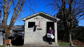 In this Wednesday, May 6, 2020, photo, Postmistress Donna DeWitt carries mail at the tiny post office on Isle Au Haut, Maine