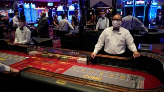 Dealers in masks wait for customers before the reopening of the D Las Vegas hotel and casino