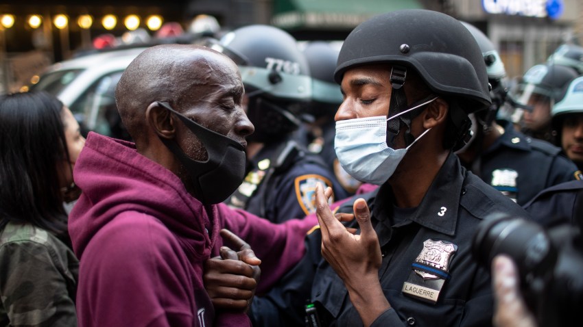 FILE - In this June 2, 2020, file photo, a protester and a police officer greet in the middle of a standoff during a solidarity rally calling for justice over the death of George Floyd in New York. Floyd, a black man, died after being restrained by Minneapolis police officers on May 25 and his death sparked protests. Black officers find themselves torn between two worlds when it comes to the protests against police brutality happening around the U.S.
