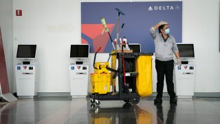 A worker cleans the Delta self check-in kiosks at Ronald Reagan Washington National Airport, May 5, 2020 in Arlington, Virginia.