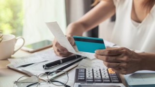 Midsection Of Businesswoman Holding Credit Card And Bill While Working At Desk