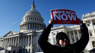 A woman holds a sign during an impeachment rally in front of the U.S. Capitol building on December 18, 2019 in Washington, DC.