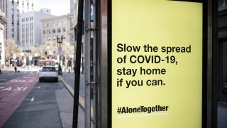 A MUNI bus stop sign displays an advertisement placed by the Center for Disease Control (CDC) reading “Slow the spread of COVID-19, stay home if you can” in San Francisco. Photographer: Michael Short/Bloomberg via Getty Images