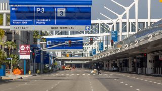 A traveler crosses the lower-lower road at LAX.