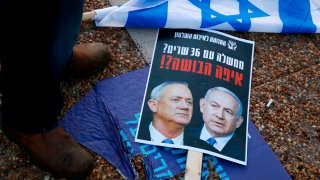 A folded Israeli flag lies near a placard left on the street