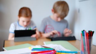 In this file photo illustration, children use iPads to complete online schoolwork at home amid the coronavirus pandemic on March 22, 2020 in Cuckfield, England.