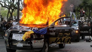 Demonstrators burn police vehicles during a protest following the death of a young man while in police custody in Guadalajara, Mexico