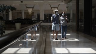 Shoppers wearing protective masks walk at a mall.