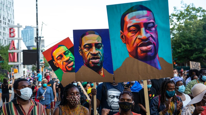 Pedestrians carry posters depicting George Floyd during a Juneteenth protest march on June 19, 2020, in the Brooklyn borough of New York City.