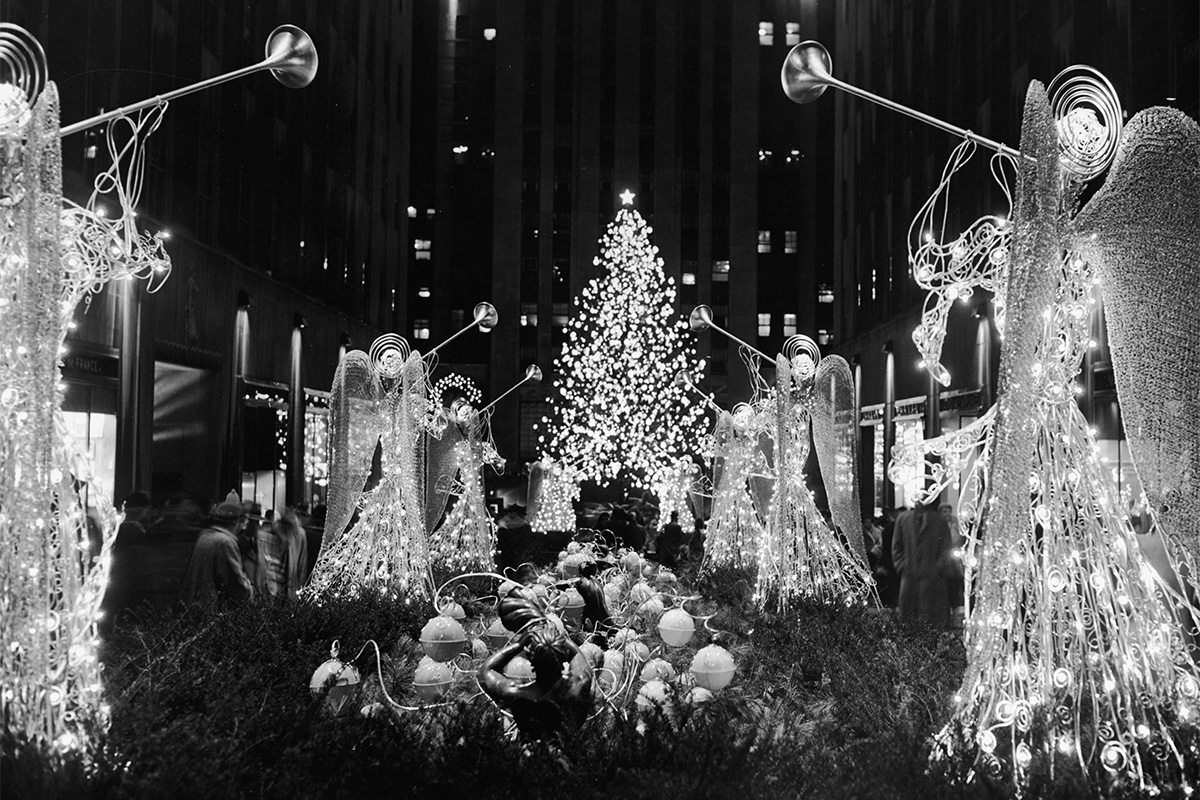 A Christmas tree and illuminated trumpeting angels adorn Rockefeller Plaza, New York, New York, circa 1950s.