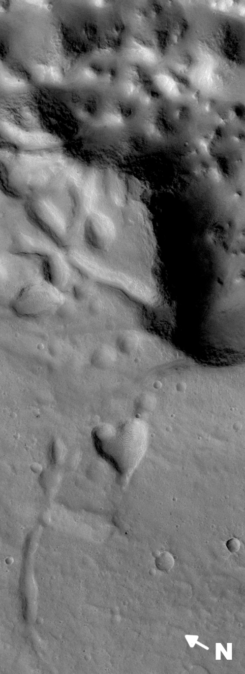 "This picture of a heart-shaped pit was taken on 26 February 2008 by the CTX camera aboard MRO. It is approximately 2 km long and is centered at 3.7° N, 29.9° W. The pit is one of many adjacent to Hydaspis Chaos, a jumbled topographic depression thought to have formed by collapse of the surface due to—perhaps—catastrophic release of groundwater." Released in 2009.