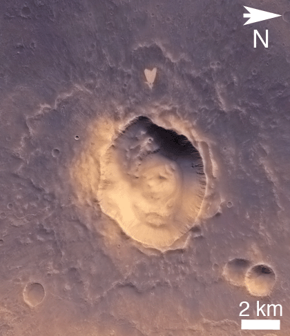 "This picture of a heart-shaped feature in Arabia Terra was taken on 23 May 2010 by the CTX camera on the MRO spacecraft. A small impact crater near the tip of the heart is responsible for the formation of the bright, heart-shaped feature. When the impact occurred, darker material on the surface was blown away, and brighter material beneath it was revealed. Some of this brighter material appears to have flowed further downslope to form the heart shape, as the small impact occurred on the ejecta blanket of a much larger impact crater." Released in 2011.