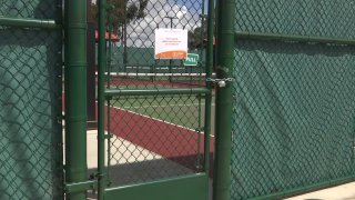 A locked gate to a tennis court.