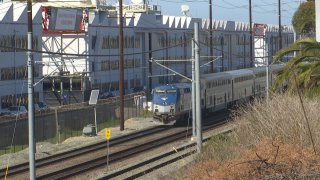 A train passes by a large white factory