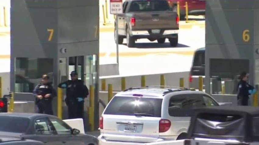 Cars wait in line next to officers in posts along the port of entry. April 24, 2020.