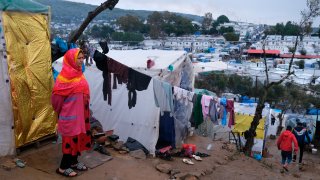 In this file photo, a migrant stands next to their makeshift tent outside the perimeter of the overcrowded Moria refugee camp on the northeastern Aegean island of Lesbos, Greece, Wednesday, March 11, 2020.