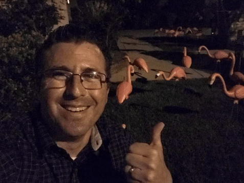 Graham Levine, who places the flamingos late at night so people can be surprised in the morning, poses next to his work.