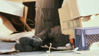 Feet of homeless person sleeping in cardboard box.