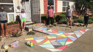 Members of the Rolando Chalk Project stand next to one of their artistic pieces.