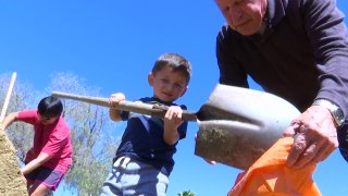 Boy scoops sand into sandbags