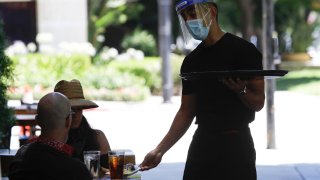 In this July 18, 2020, file photo, a waiter takes a food order in Burbank, Calif.