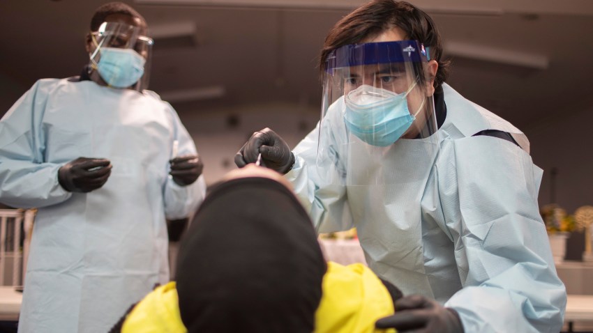 Health care workers use a nasal swab to test a person for COVID-19 at a pop up testing site in Pembroke Park, Fla., on July 22, 2020