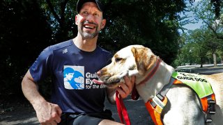 Thomas Panek pauses with his Labrador retriever, Blaze, a trained guide dog, after running in Central Park, July 23, 2020, in New York. Panek, an accomplished runner who is blind, developed a canine running guide training program.