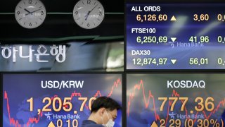A currency trader wearing a face mask watches computer monitors near the screens showing the foreign exchange rate between U.S. dollar and South Korean won at the foreign exchange dealing room in Seoul, South Korea, Friday, July 17, 2020.
