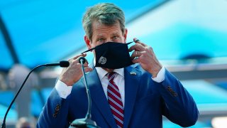 Georgia Gov. Brian Kemp puts on a mask after speaking at a press conference announcing statewide expanded COVID testing, Aug. 10, 2020, in Atlanta.