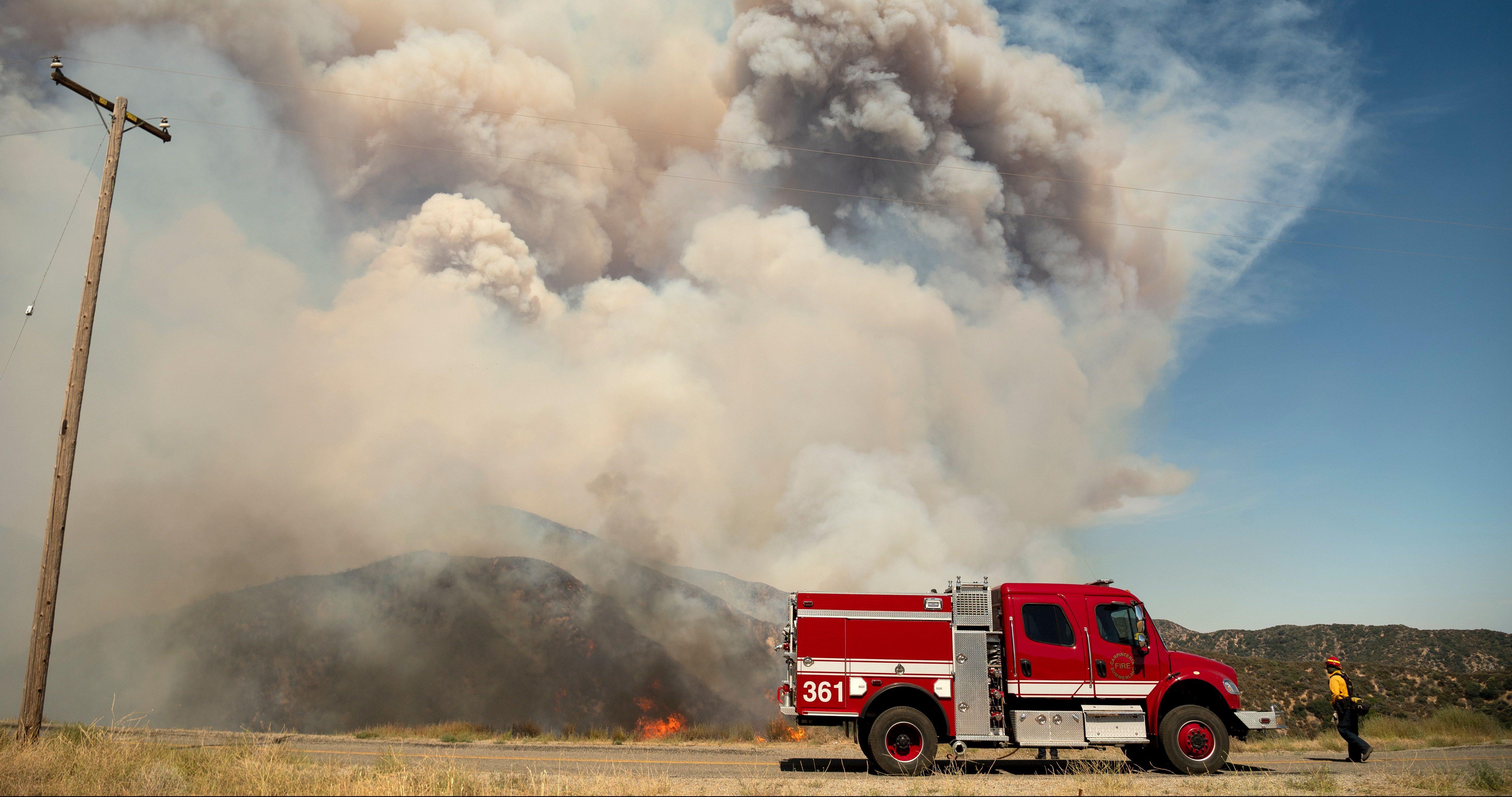 A firefighter walks back to his truck near a pyrocumulus ash plume during the Apple fire near Banning, California on August 1, 2020. – 4,125 acres have burn in Cherry Valley, about 2,000 people have received evacuation orders in the afternoon of August 1. (Photo by JOSH EDELSON / AFP) (Photo by JOSH EDELSON/AFP via Getty Images)