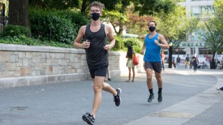 People wearing masks run in Union Square on August 09, 2020 in New York City.