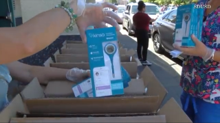 An SDUSD employee holds a Kinsa digital thermometer at a food distribution.