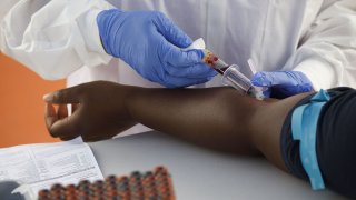 A phlebotomist wearing protective gloves draws blood from a patient for a COVID-19 antibody test at a GUARDaHEART Foundation testing site in Los Angeles, Aug. 5, 2020.