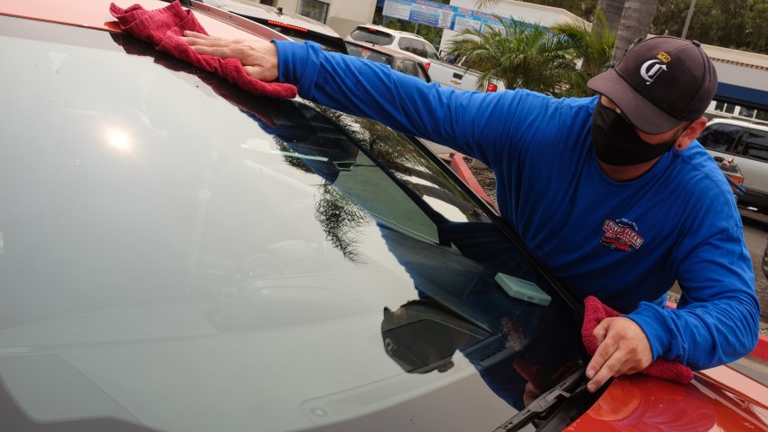 A worker at National City Car Wash dries a customer’s window.