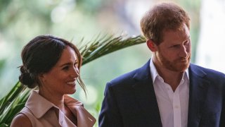 Britain's Prince Harry, Duke of Sussex(R) and Meghan, the Duchess of Sussex(L) stand on the stage at the British High Commissioner residency in Johannesburg where they will meet with Graca Machel, widow of former South African president Nelson Mandela, in Johannesburg, on October 2, 2019. - Prince Harry recalled the hounding of his late mother Diana to denounce media treatment of his wife Meghan Markle, as the couple launched legal action against a British tabloid for invasion of privacy.