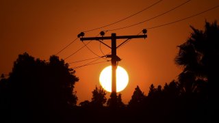 The sun sets behind power lines.