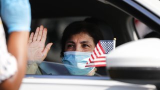SANTA ANA, CALIFORNIA – JULY 29: A new U.S. citizen sits in a vehicle while being sworn in by an immigration service officer at a drive-in naturalization ceremony amid the COVID-19 pandemic on July 29, 2020 in Santa Ana, California. The naturalization ceremony welcomed around 268 immigrants who took the citizenship oath and pledged allegiance to the American flag as the spread of the coronavirus continues. U.S. Citizenship and Immigration Services temporarily suspended in-person ceremonies for nearly three months to help slow the spread of COVID-19. (Photo by Mario Tama/Getty Images)