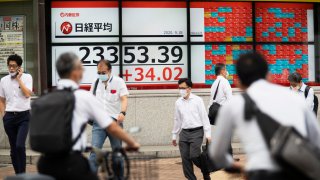 Men walk by screens showing Japan's Nikkei 225 index at a securities firm in Tokyo on Friday, Sept. 18, 2020.
