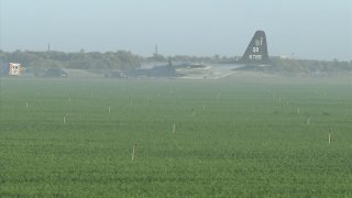 A KC-130J assigned to Marine Corps Air Station Miramar sitting in a field near an airport in Thermal, CA following a mid-air collision with an F-35B