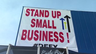 A sign that reads, "Stand Up Small Business #Defy" rests above Rudford's Restaurant.
