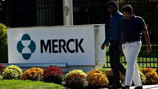 Employees walk past a Merck sign in front of the company’s building in Summit, New Jersey.